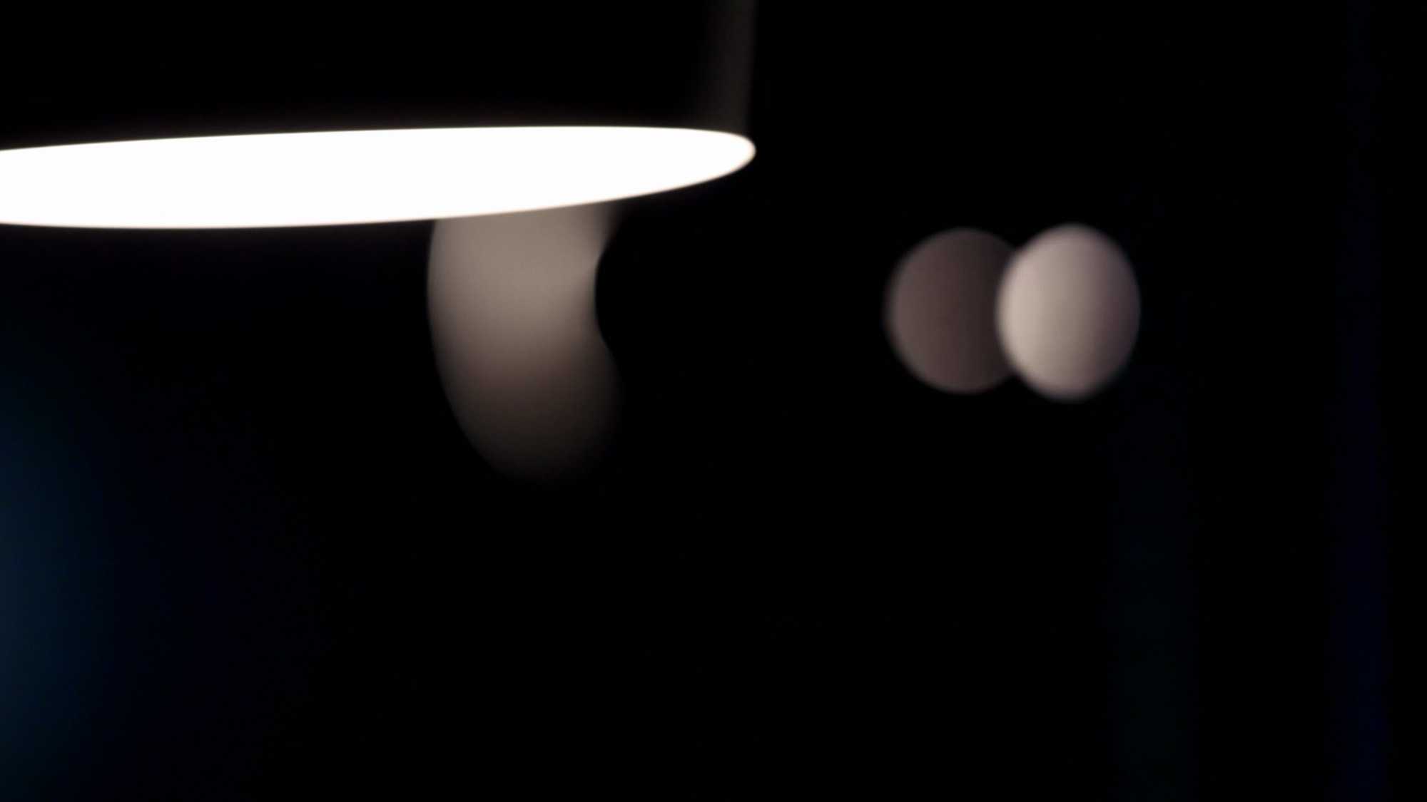 Das Bild zeigt einen dunklen Hintergrund. Von der Decke hängt eine Lampe. Von dieser Lampe gehen Lichtpunkte aus. Das Bild dient als Sliderbild für den Portfolioeintrag BMW Quiet Motion von Panda Pictures.