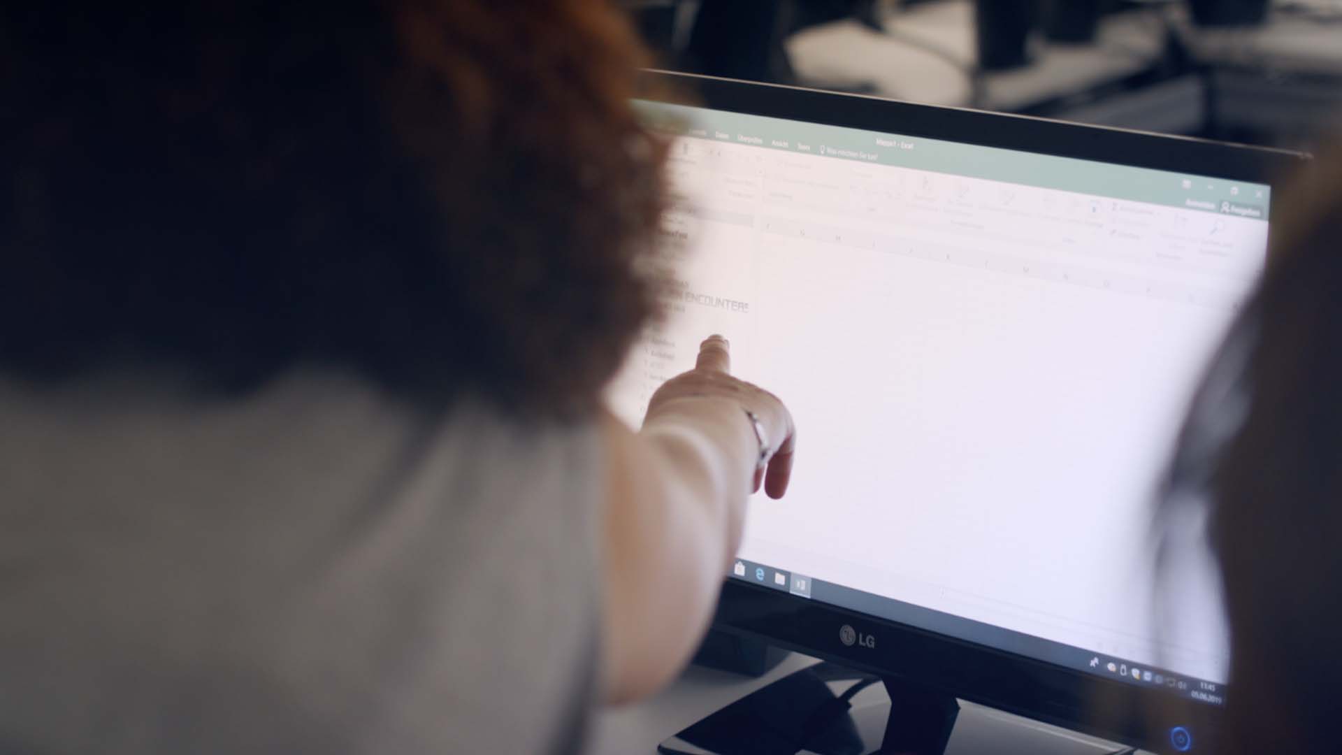 Das Bild zeigt einen Computerbildschirm vor dem eine Frau steht. Sie zeigt mit ihrem Finger auf den Bildschirm. Das Bild dient als Sliderbild für den Portfolioeintrag Bayerischer Volkshochschulverband von Panda Pictures.